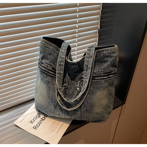 Détail du sac cabas en denim bleu foncé avec fermetures éclair et larges bandoulières