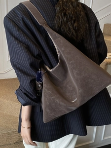 Large dark brown suede tote bag for women worn by a model in a navy striped suit