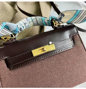 Detail of golden metal twist lock on contrast matte suede and smooth leather handbag