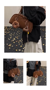 Detail of a brown matte suede tote bag with contrast stitching and plush charm accessories