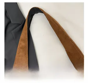 Detail of a brown suede tote bag featuring a wide shoulder strap and neat stitching