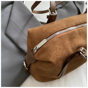 Close-up of silver zipper detail and brown suede texture on a stylish Boston tote bag