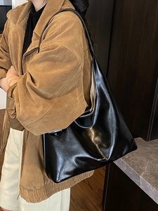 Minimalist black PU leather tote bag shown on model with sleek shoulder strap