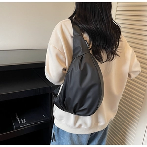 Détail d'un sac bandoulière en nylon noir avec forme en goutte d'eau et étiquette tissée