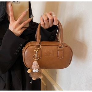 Gros plan d'un sac à main marron en similicuir avec logo gaufré et pendentif en peluche