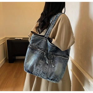 Détail du grand sac cabas en denim bleu vintage avec double poche zippée et pompons