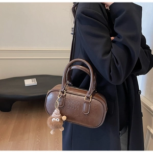 Détail du sac Boston marron foncé rétro avec pendentif peluche et logo de marque