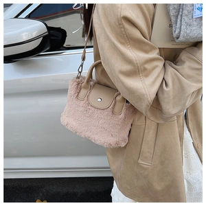 Detail of pink faux fur crossbody bag with beige leather trim and metal hardware