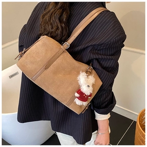 Detail view of brown faux suede tote bag with a cute bear charm on a female model