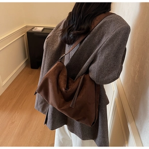 Detail van een grote bruine suède shopper gecombineerd met een grijze blazer look