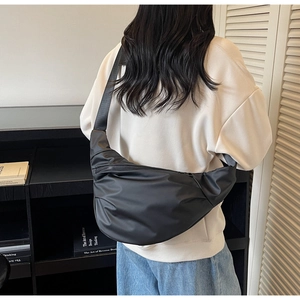 Détail d'un sac bandoulière noir en nylon mat avec large sangle porté par un mannequin