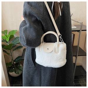 Detail of the white faux fur texture and leather handle on the crossbody bag