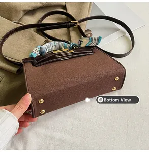 Bottom view of vintage brown matte handbag with silk scarf and four gold metal feet