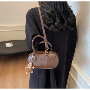 Sac Boston rétro marron avec gaufrage ATN, texture cuir lisse et breloque monstre en peluche