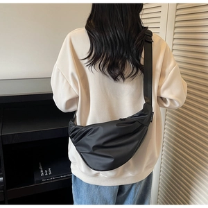 Vue arrière d'un sac bandoulière en nylon noir porté par un mannequin à domicile
