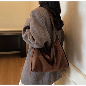 Detail van donkerbruine suède hobo-tas met grote capaciteit en zachte matte textuur
