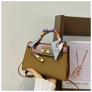 Close-up of brown matte handbag with silk scarf handle and golden metal twist lock detail