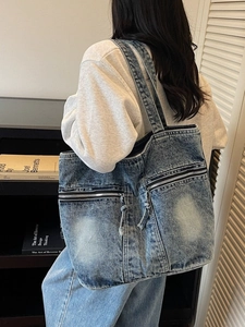 Grand sac fourre-tout en denim bleu délavé avec poches zippées et détails à franges