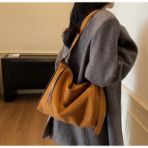Detail van de tan suede hobo tas gedragen over een grijze wollen jas voor de herfst