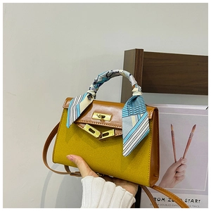 Detail of yellow suede handbag with silk scarf wrapped handle and gold metal lock
