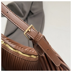 Close-up of brown pleated shoulder bag showing gold metal hardware and texture