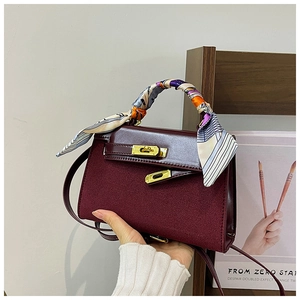 Detailed view of burgundy matte handbag with patterned silk scarf and gold hardware