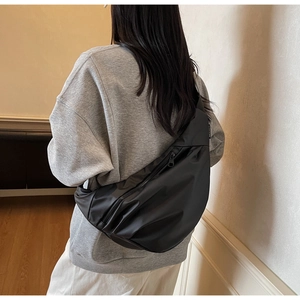 Vue détaillée d'un sac bandoulière minimaliste en nylon noir porté sur le dos