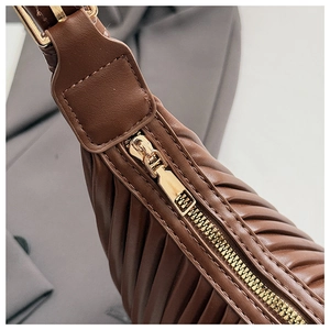 Detailed view of brown pleated cloud bag featuring vertical stripes and gold zipper