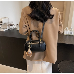 Détail d'un sac en cuir PU noir texturé avec logo et charmant pendentif monstre