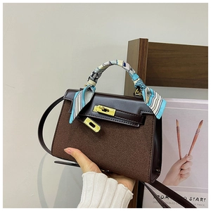 Detailed view of brown matte leather handbag featuring a silk scarf wrapped handle