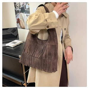 Detail of a dark brown suede tote bag featuring layered fringe and a retro bohemian style