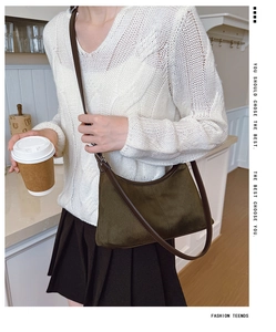 Deep green canvas crescent shoulder bag shown on model with white sweater and dark skirt