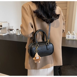 Détail du sac Boston en cuir noir texturé avec logo ATN gaufré et charm en peluche