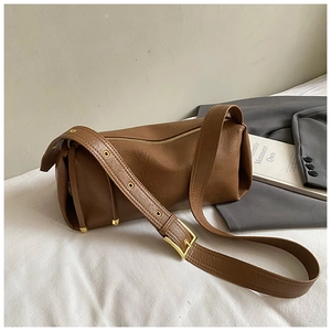 Détail du sac marron avec motif litchi, boucle dorée et bandoulière large ajustable