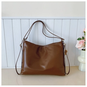 Detail view of smooth dark brown leather texture and gold hardware on the shoulder bag