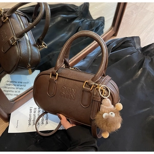 Détail du sac Boston marron foncé avec embossage ATN et breloque monstre en peluche