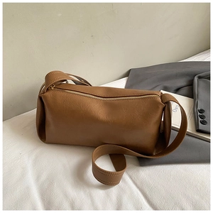 Détail d'un sac baguette marron avec fermeture éclair dorée sur fond blanc