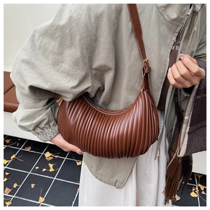 Brown pleated crescent bag with adjustable strap shown styled on model in autumn setting