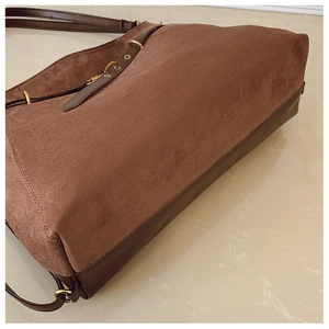 Detail view of chocolate brown suede tote bag with smooth leather trim and gold hardware