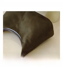 Macro shot of dark olive suede fabric texture with brown leather trim and silver metal hardware