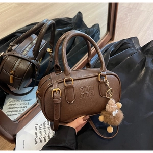 Gros plan du sac Boston marron rétro avec cuir texturé et breloque en peluche