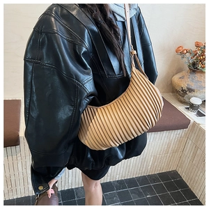Close-up of khaki pleated crescent bag showing fine accordion texture and strap detail