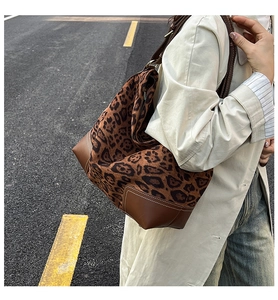 Detail of leopard print tote bag with brown leather trim and contrast stitching on the street
