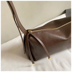 Vue détaillée du sac cylindre marron foncé montrant la texture PU et le zip doré