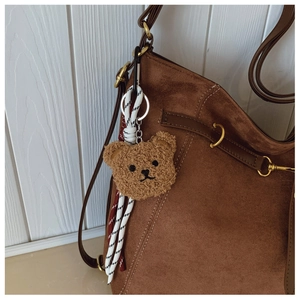 Close-up of a cute brown plush bear charm accessory on a fuzzy autumn tote bag