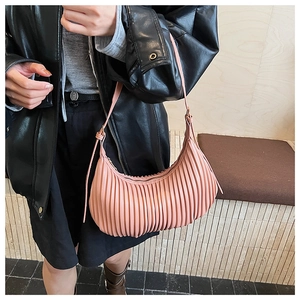 Pink pleated crescent shoulder bag shown on model with chic black leather jacket style