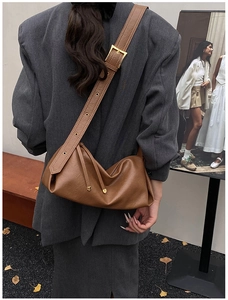 Vue latérale d'un grand sac hobo en cuir souple marron avec large bandoulière et pompon