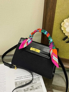 Elegant black trapezoid handbag with gold clasp and silk scarf wrapped around the handle