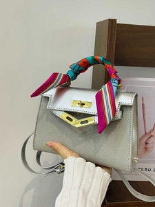Silver trapezoid handbag with matte finish and colorful silk scarf wrapped around handle