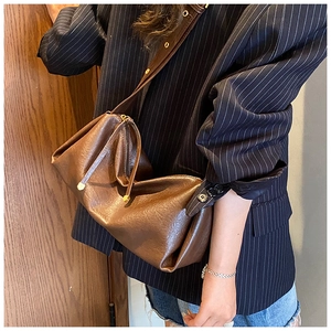 Détail macro du sac baguette rétro marron avec design plissé et fermeture éclair dorée